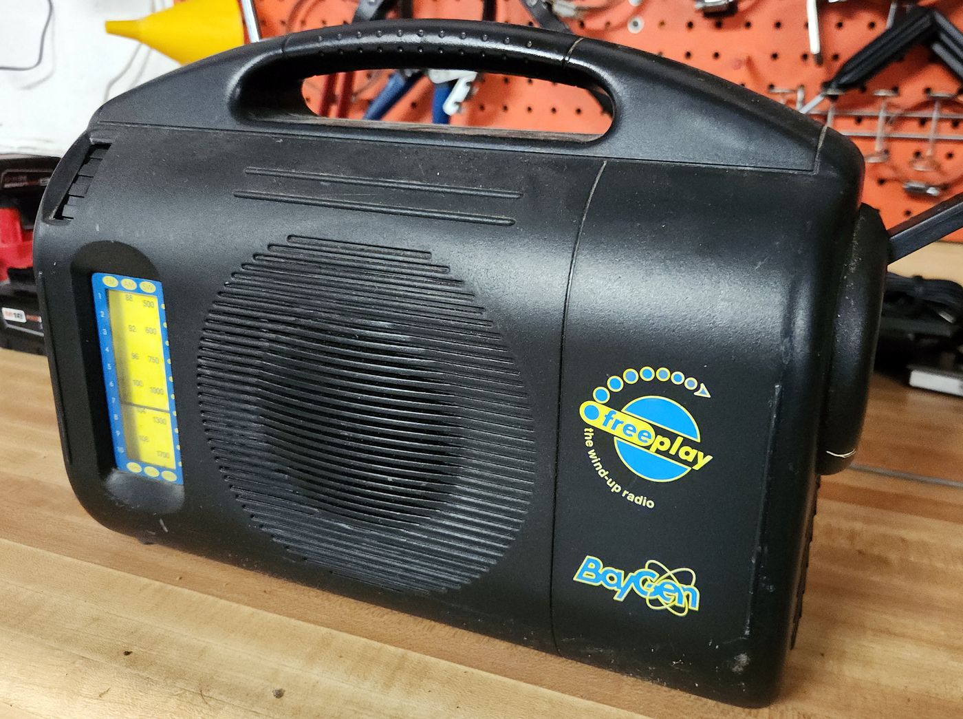 An original BayGen Freeplay wind-up radio on a workbench