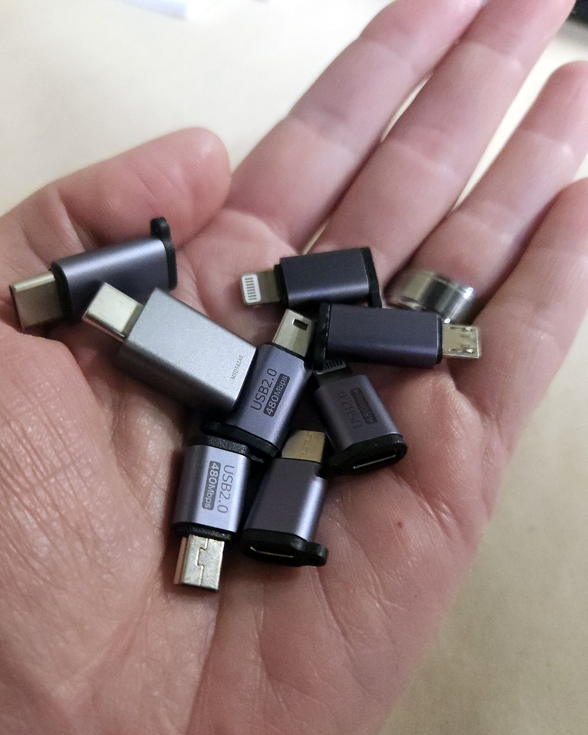 A handful of USB adapters of every connector type in an open palm